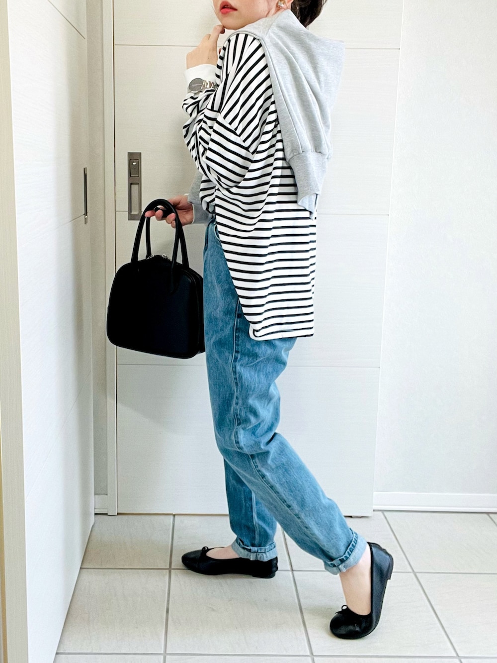 ブラック系のTシャツ/カットソー、グレー系のカーディガン/ボレロ、ブルー系のデニムパンツを着用したレディースの春コーディネートの4枚目の写真