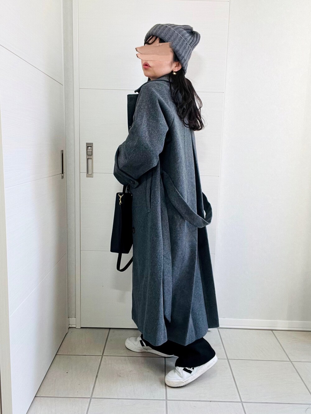 グレー系のステンカラーコート、グレー系のニット/セーター、ブラック系のスラックスを着用したレディースの冬コーディネートの4枚目の写真