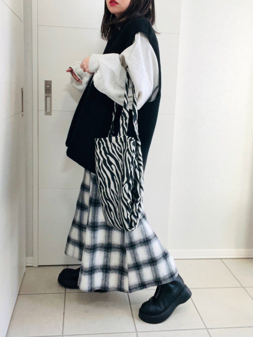 ブラック系のベスト、グレー系のスウェット、ホワイト系のスカートを着用したレディースの冬コーディネートの5枚目の写真