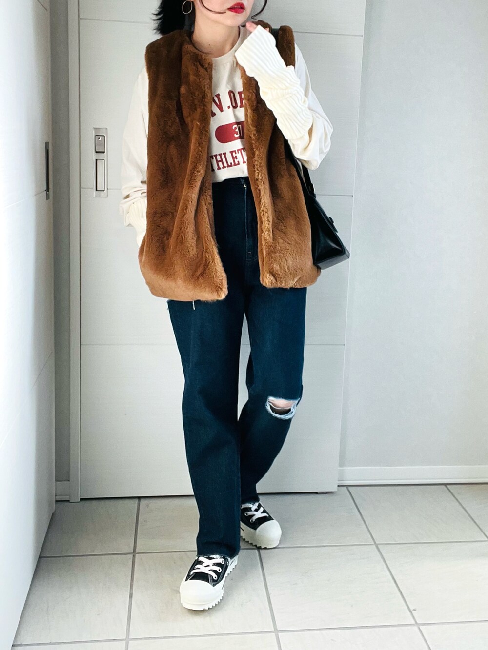 ベージュ系のTシャツ/カットソー、ブラウン系のベスト、ブルー系のデニムパンツを着用したレディースの秋コーディネートの3枚目の写真