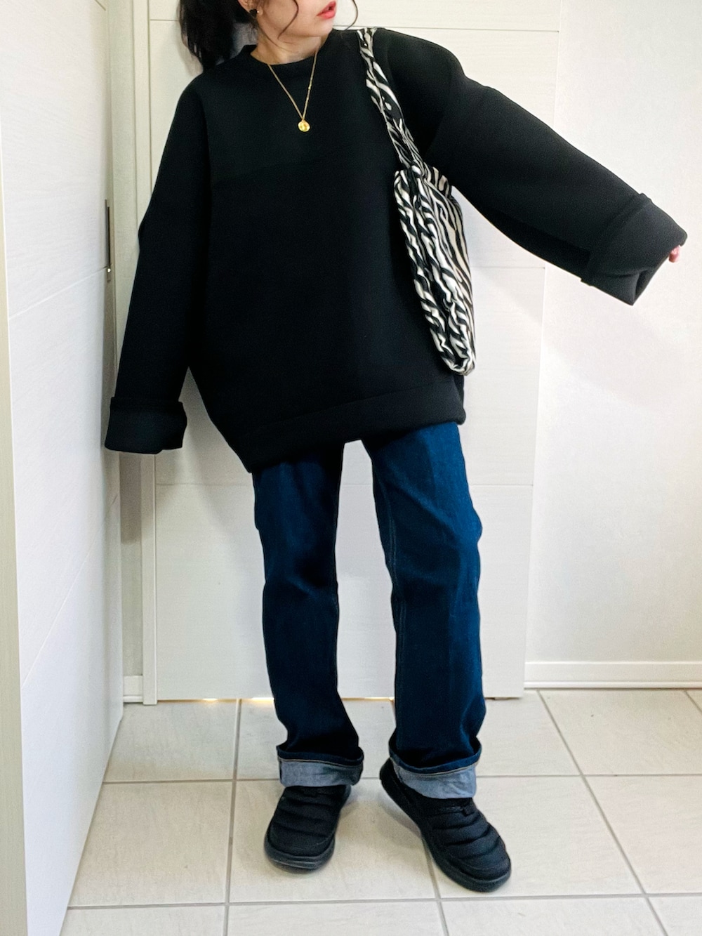 ブラック系のスウェット、ホワイト系のダウンジャケット/コート、ブルー系のデニムパンツを着用したレディースの冬コーディネートの2枚目の写真