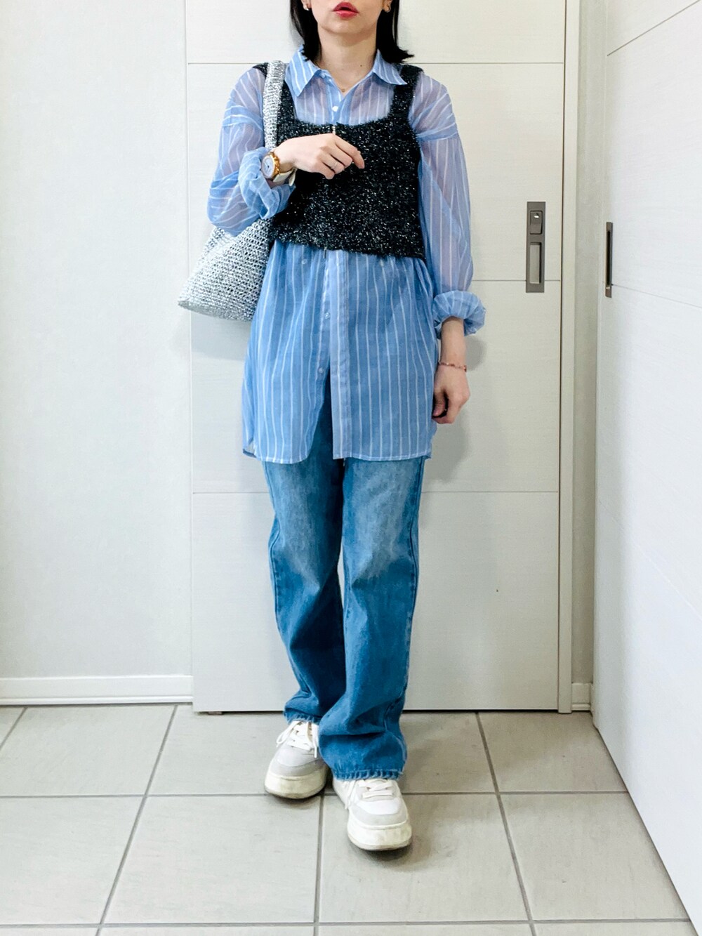 ブルー系のシャツ/ブラウス、ブラック系のベスト、ブルー系のデニムパンツを着用したレディースの春コーディネートの4枚目の写真