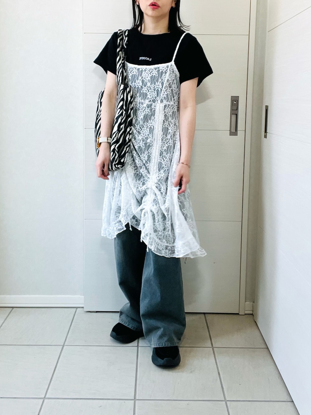 ホワイト系のチュニック、ブラック系のTシャツ/カットソー、ブルー系のデニムパンツを着用したレディースの春コーディネートの5枚目の写真