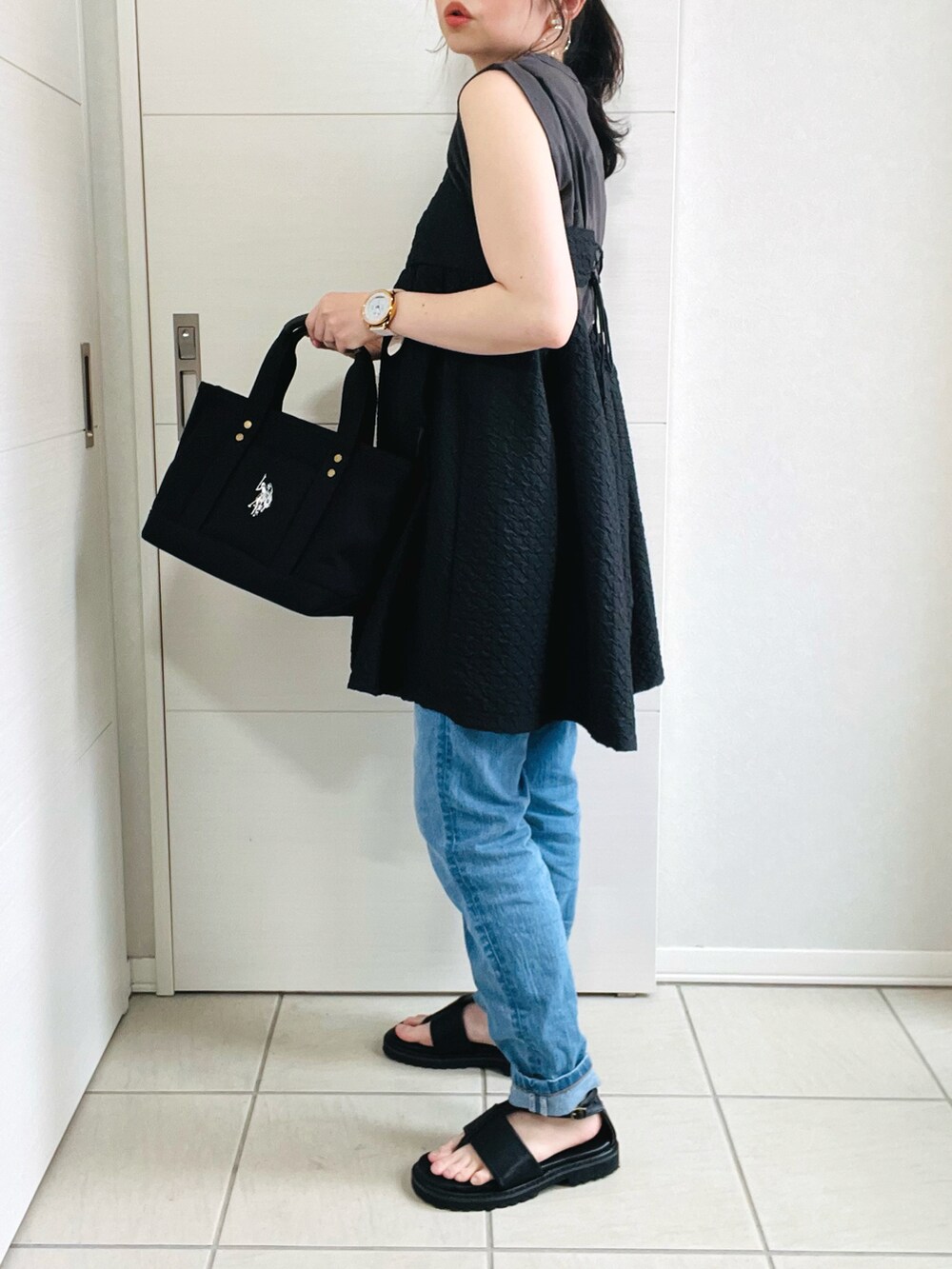 ブラック系のトートバッグ、ブラック系のワンピース、ブルー系のデニムパンツを着用したレディースの夏コーディネートの5枚目の写真