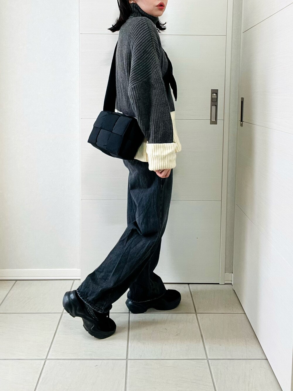 グレー系のニット/セーター、ブラック系のデニムパンツ、ブラック系のスニーカーを着用したレディースの冬コーディネートの5枚目の写真