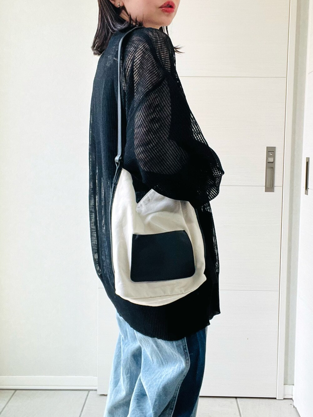 ブラック系のカーディガン/ボレロ、ブルー系のデニムパンツ、ホワイト系のスニーカーを着用したレディースの夏コーディネートの3枚目の写真