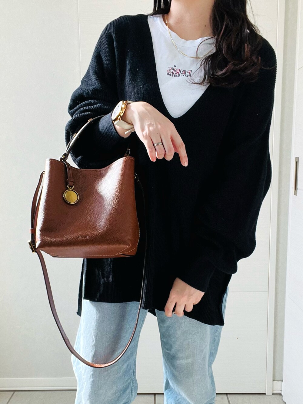 ブラウン系のショルダーバッグ、ホワイト系のTシャツ/カットソー、ブラック系のニット/セーターを着用したレディースの秋コーディネートの2枚目の写真