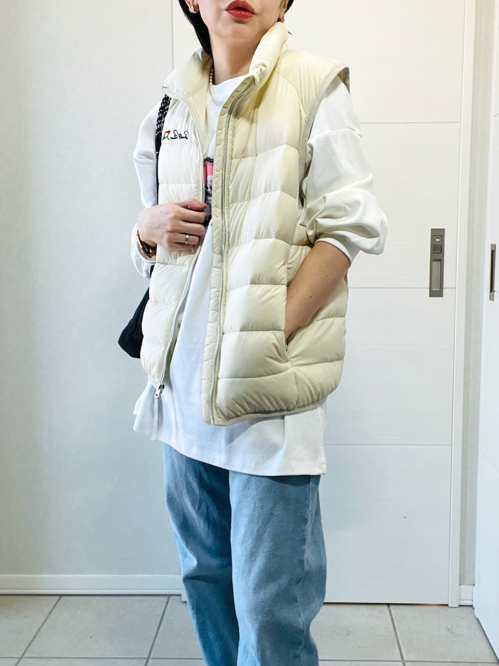 ホワイト系のダウンベスト、ホワイト系のTシャツ/カットソー、ブルー系のデニムパンツを着用したレディースの秋コーディネートの4枚目の写真