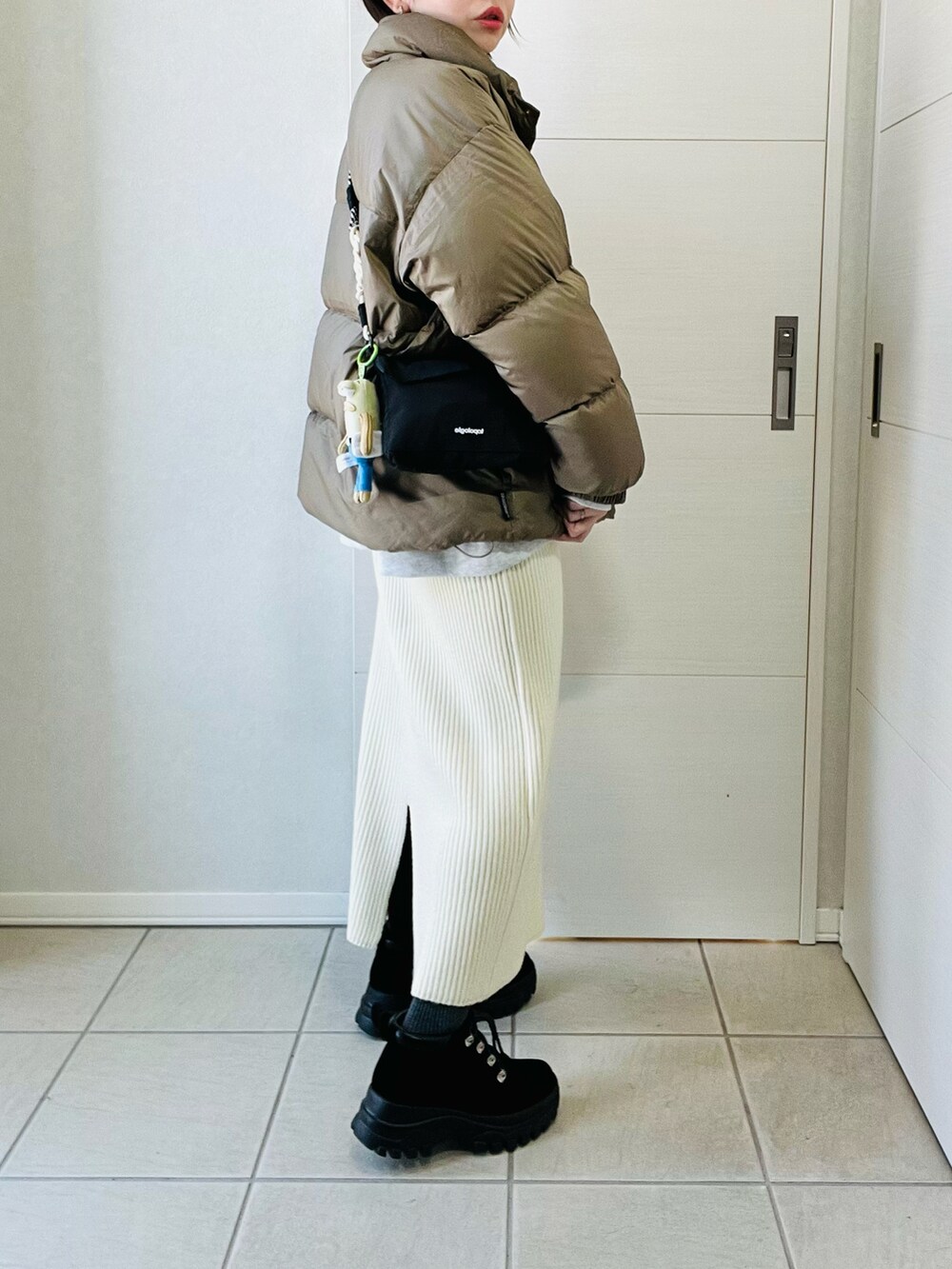 ベージュ系のダウンジャケット/コート、ホワイト系のスカート、ブラック系のブーツを着用したレディースの冬コーディネートの4枚目の写真