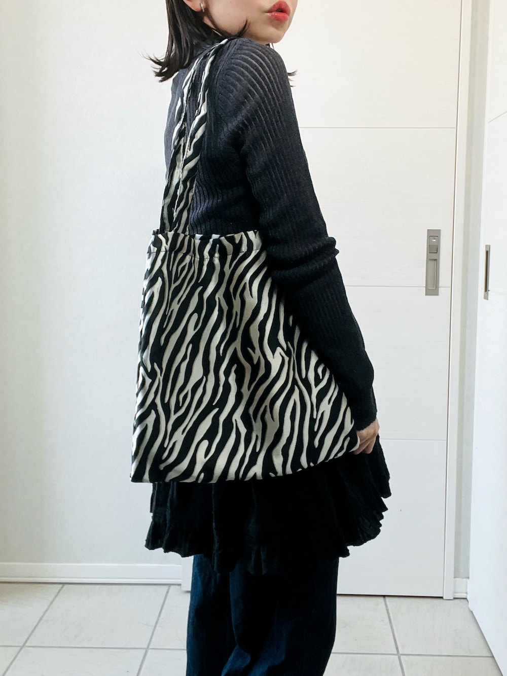 グレー系のカーディガン/ボレロ、ブラック系のワンピース、ブルー系のデニムパンツを着用したレディースの春コーディネートの3枚目の写真