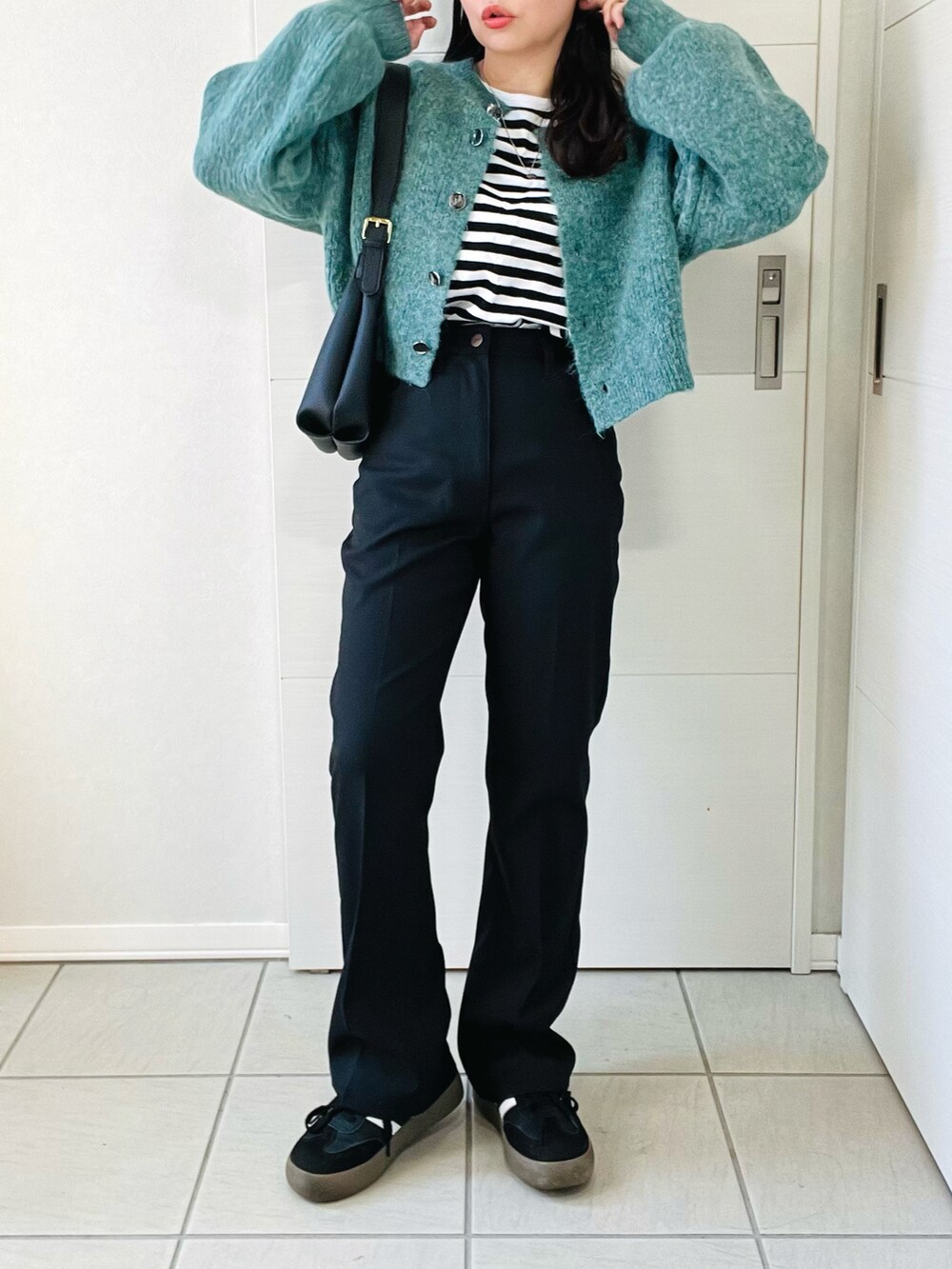 グリーン系のカーディガン/ボレロ、ブラック系のTシャツ/カットソー、ブラック系のスラックスを着用したレディースの秋コーディネートの4枚目の写真