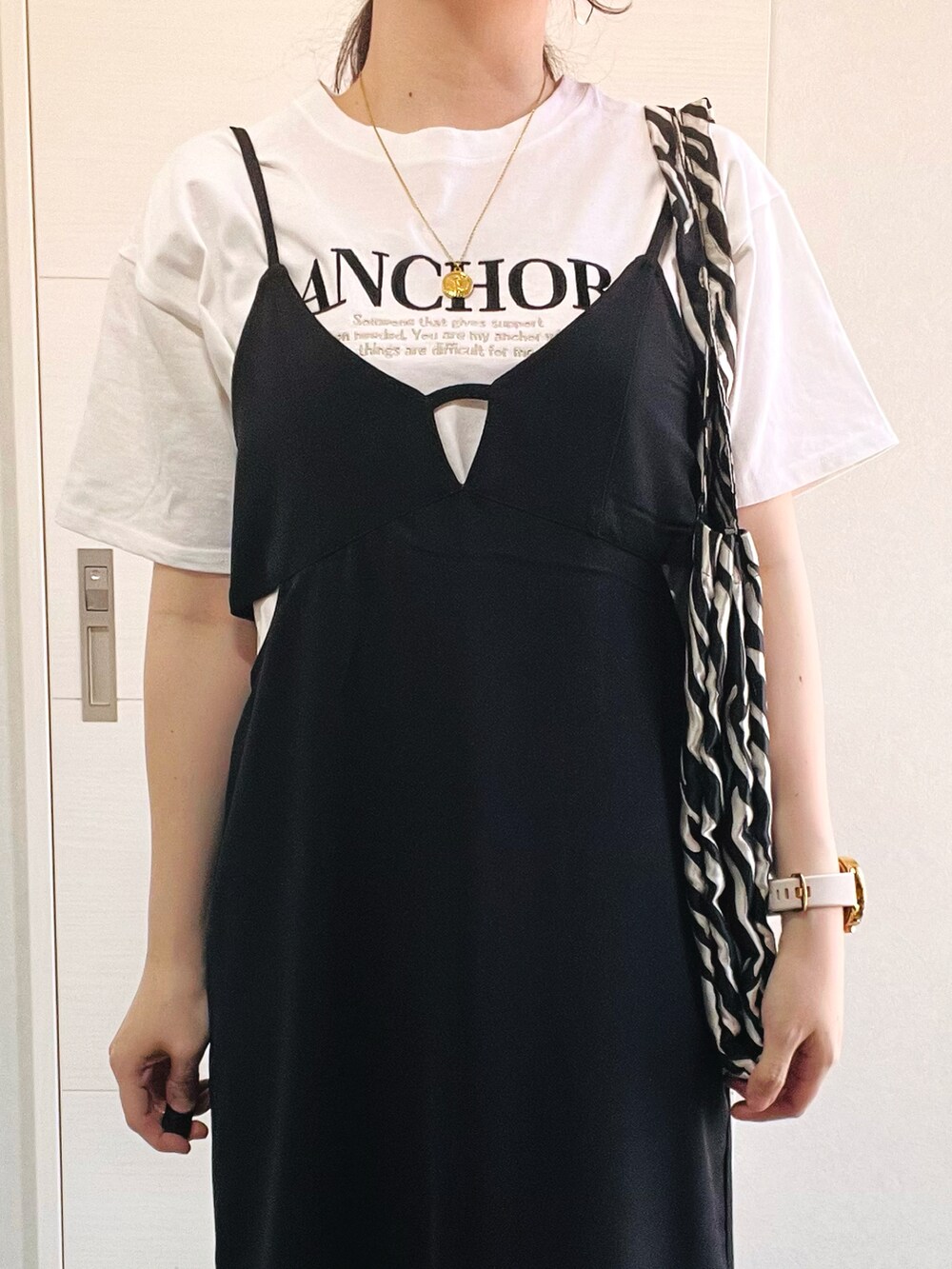 ホワイト系のTシャツ/カットソー、ブラック系のジャンパースカート、ブラック系のスニーカーを着用したレディースの春コーディネートの3枚目の写真