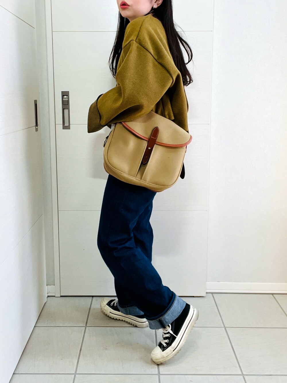 グリーン系のワンピース、ブルー系のデニムパンツ、ブラック系のスニーカーを着用したレディースの冬コーディネートの5枚目の写真