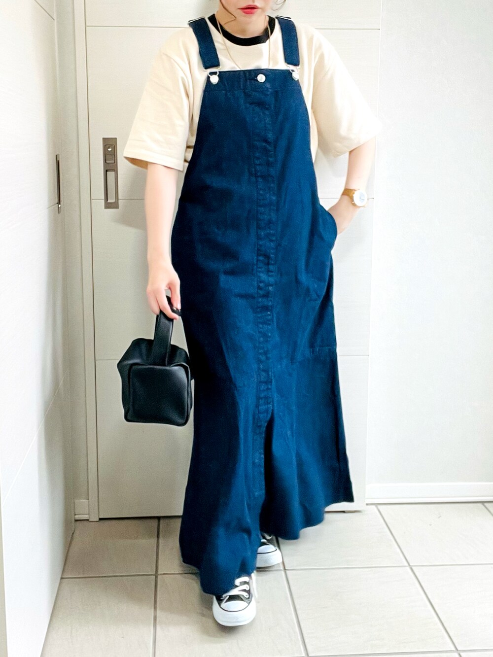 ブルー系のジャンパースカート、ベージュ系のTシャツ/カットソー、ブラック系のスニーカーを着用したレディースの夏コーディネートの2枚目の写真