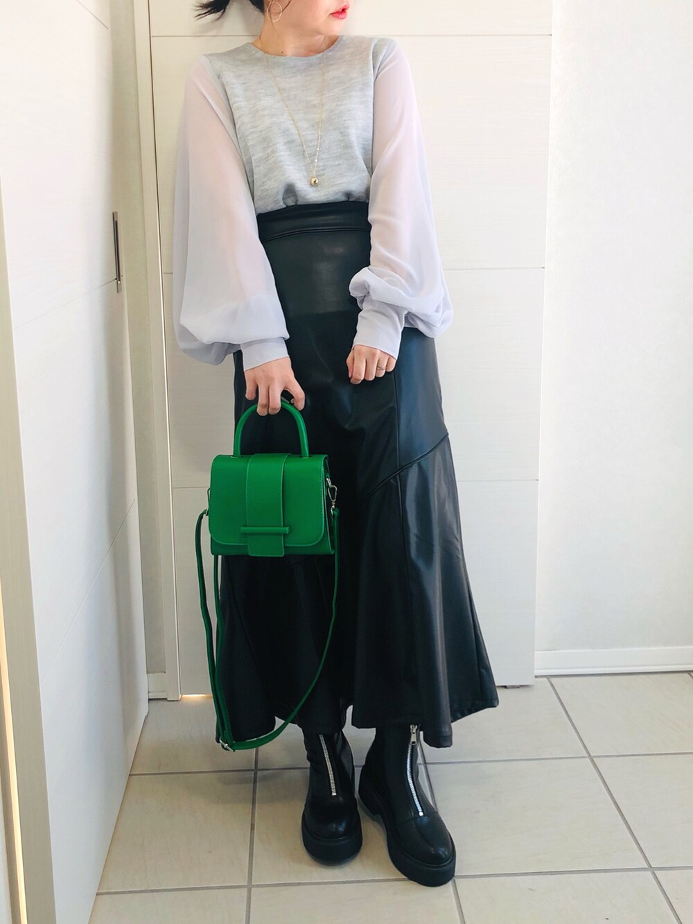 グレー系のTシャツ/カットソー、ブラック系のスカート、ブラック系のブーツを着用したレディースの冬コーディネートの3枚目の写真