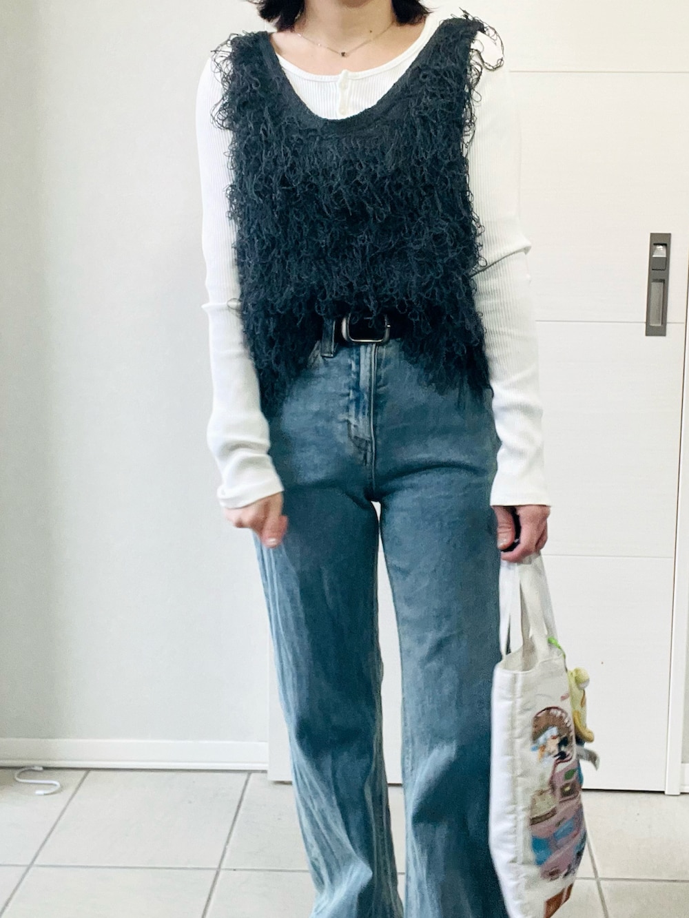 グレー系のベスト、グレー系のスニーカー、ブルー系のデニムパンツを着用したレディースの春コーディネートの2枚目の写真