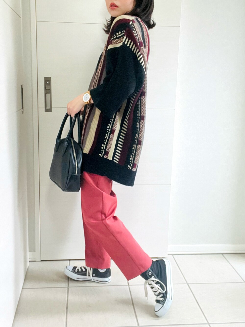 レッド系のニット/セーター、レッド系のスラックス、ブラック系のスニーカーを着用したレディースの夏コーディネートの3枚目の写真