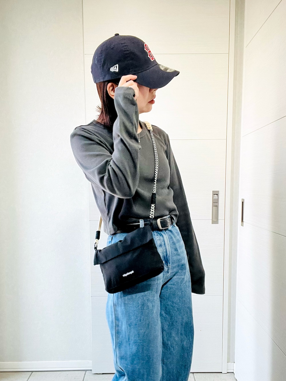 グレー系のスニーカー、グレー系のTシャツ/カットソー、ブラック系のショルダーバッグを着用したレディースの夏コーディネートの3枚目の写真