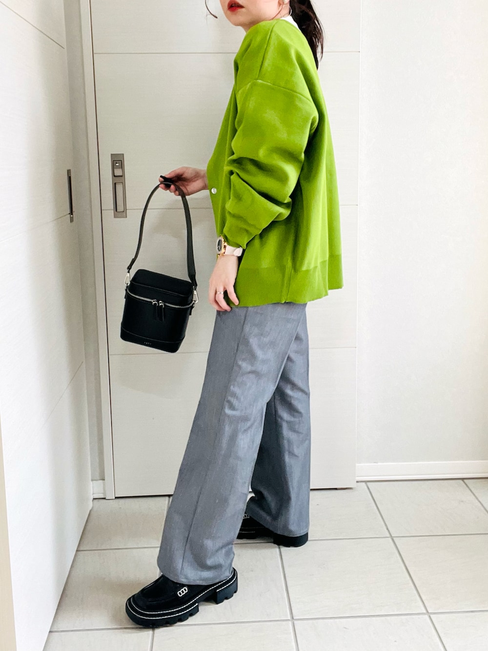 グリーン系のカーディガン/ボレロ、ホワイト系のTシャツ/カットソー、グレー系のスラックスを着用したレディースの春コーディネートの4枚目の写真