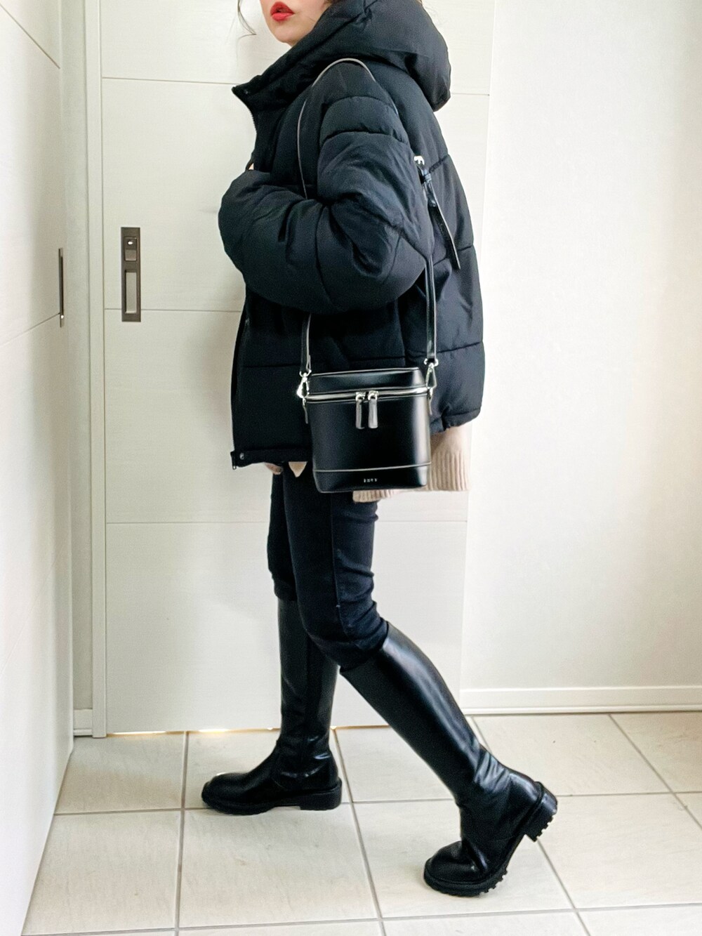 ブラック系のダウンジャケット/コート、ベージュ系のニット/セーター、ブラック系のデニムパンツを着用したレディースの冬コーディネートの4枚目の写真