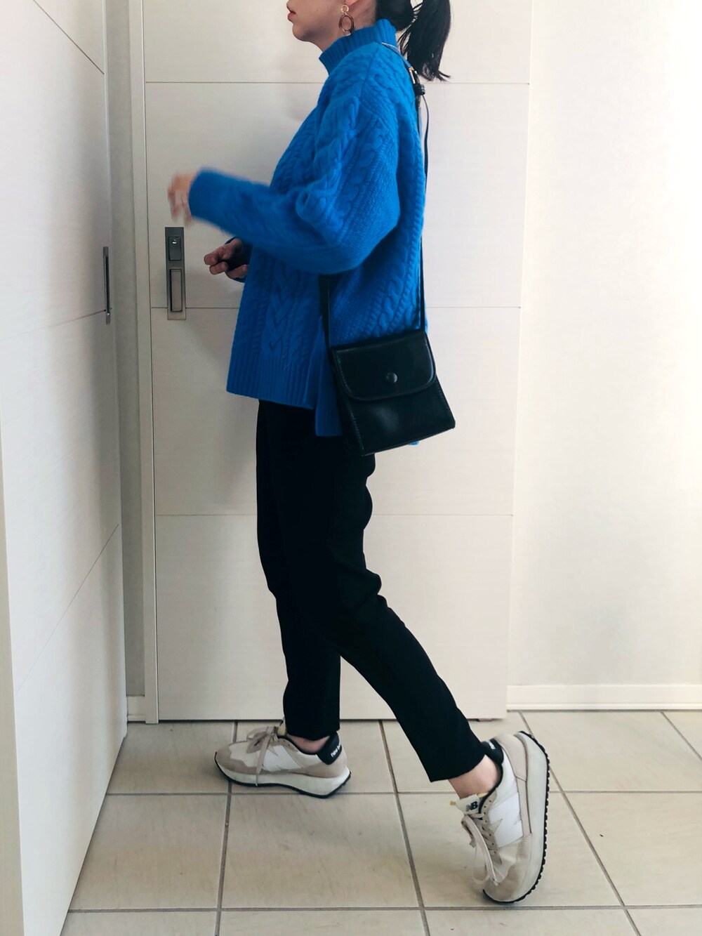 ブルー系のニット/セーター、ブラック系のパンツ、ホワイト系のスニーカーを着用したレディースの秋コーディネートの3枚目の写真