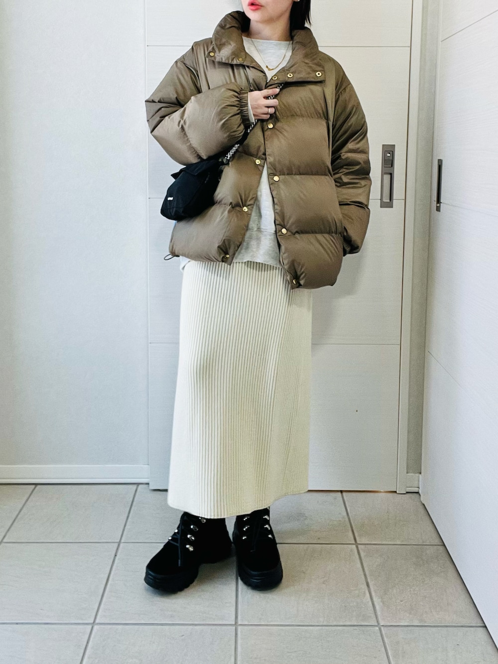 ベージュ系のダウンジャケット/コート、ホワイト系のスカート、ブラック系のブーツを着用したレディースの冬コーディネートの5枚目の写真