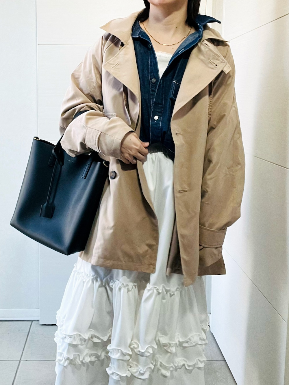 ベージュ系のトレンチコート、ブルー系のシャツ/ブラウス、ホワイト系のスカートを着用したレディースの春コーディネートの2枚目の写真