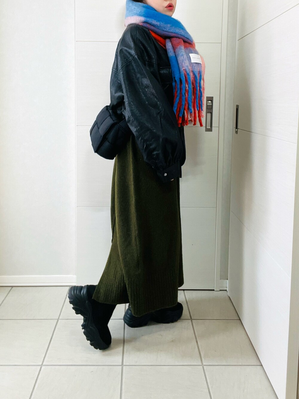 ブラック系のブルゾン、グリーン系のワンピース、ブラック系のブーツを着用したレディースの冬コーディネートの3枚目の写真