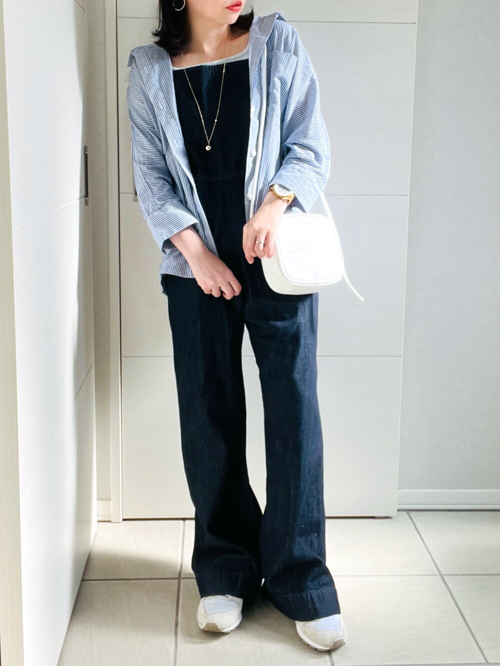 ブルー系のシャツ/ブラウス、ブルー系のサロペット/オーバーオール、ホワイト系のスニーカーを着用したレディースの夏コーディネートの2枚目の写真