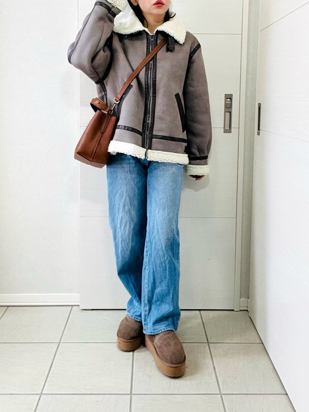 グレー系のムートンコート、ブルー系のデニムパンツ、ベージュ系のスリッポンを着用したレディースの冬コーディネートの3枚目の写真