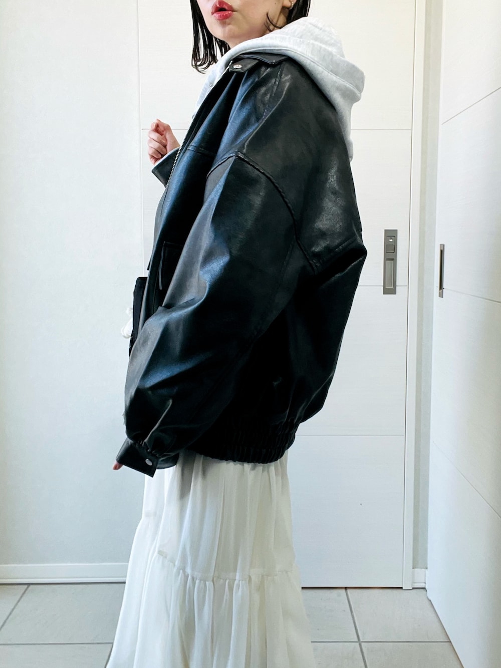 ブラック系のブルゾン、グレー系のパーカー、ホワイト系のスカートを着用したレディースの冬コーディネートの3枚目の写真