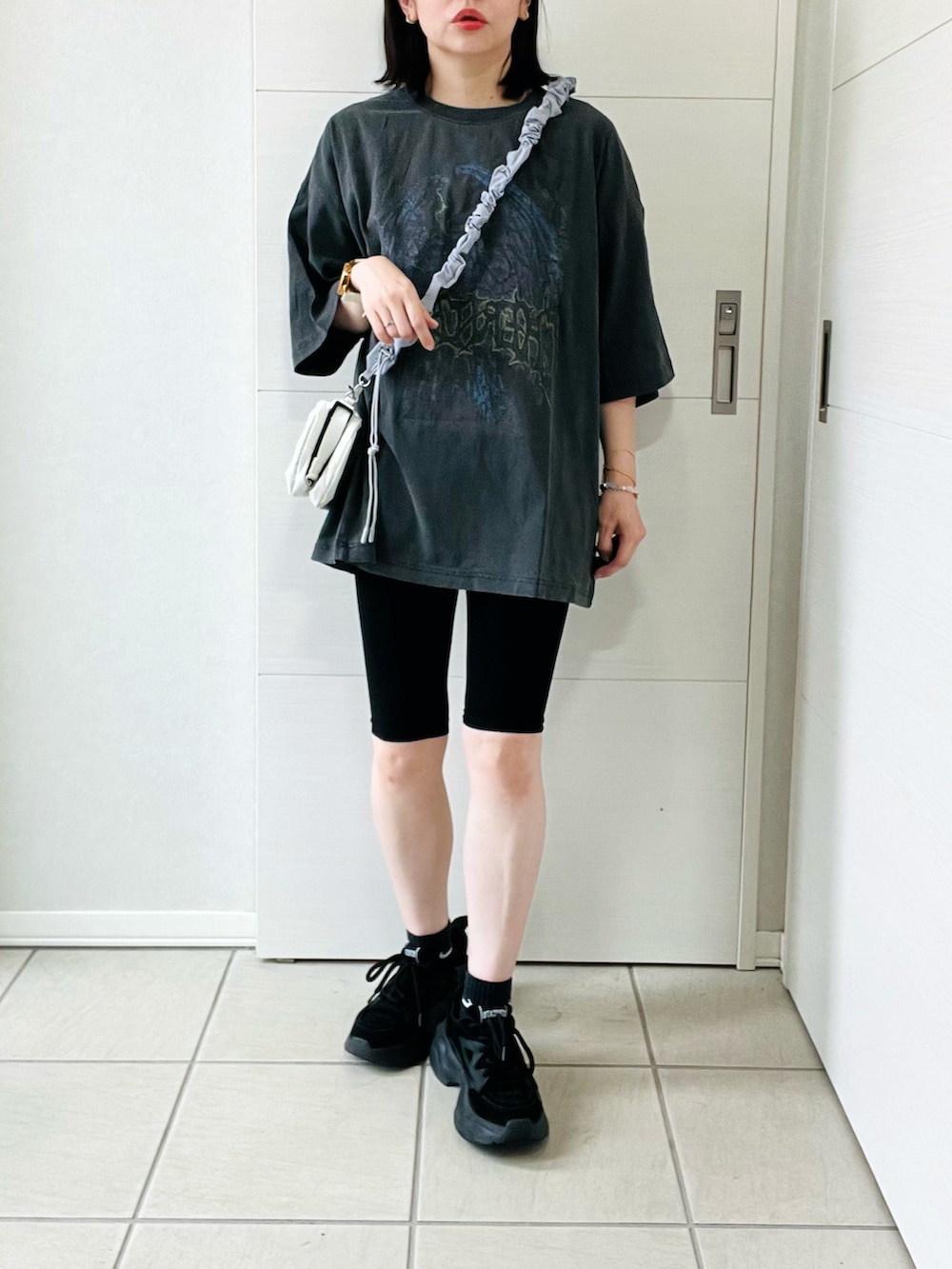 グレー系のTシャツ/カットソー、ブラック系のスニーカー、ホワイト系のショルダーバッグを着用したレディースの夏コーディネートの4枚目の写真