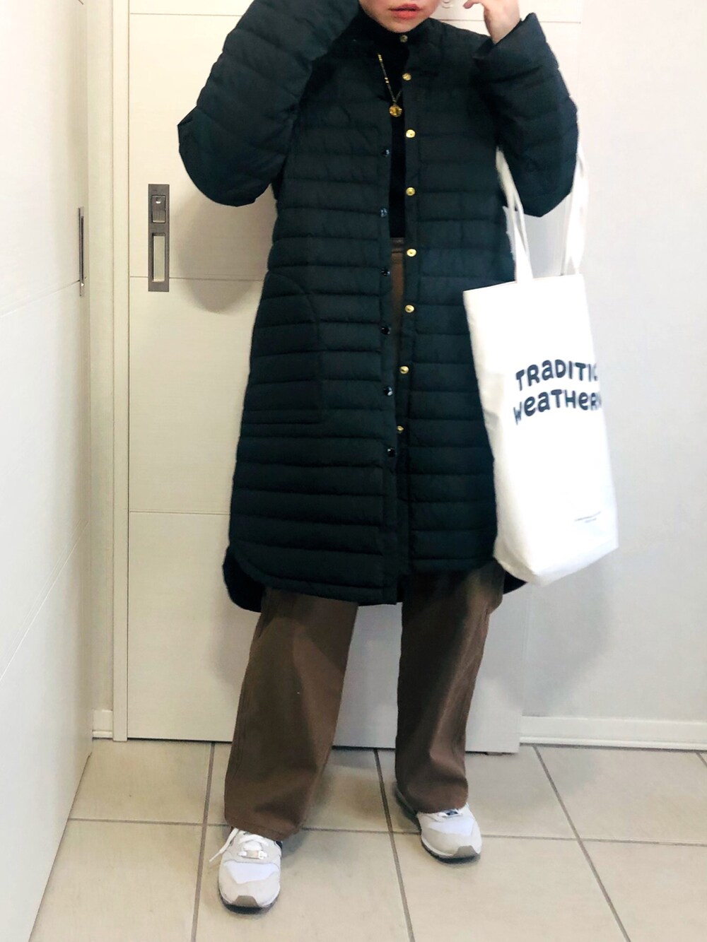 ブラック系のダウンジャケット/コート、ブラック系のニット/セーター、ブラウン系のチノパンツを着用したレディースの冬コーディネートの4枚目の写真