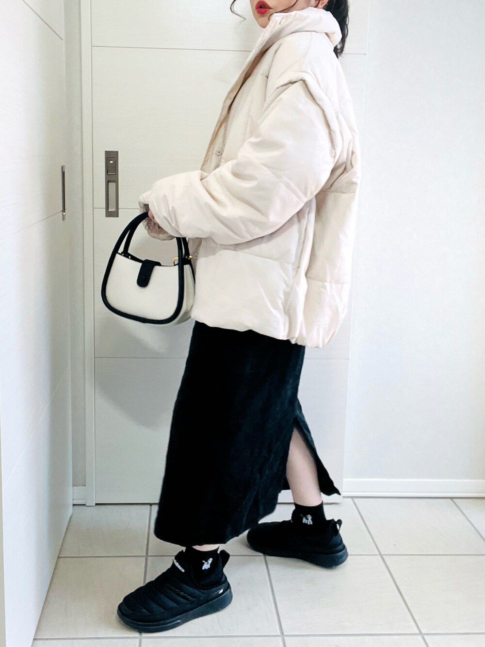 ホワイト系のダウンジャケット/コート、ホワイト系のスウェット、ブラック系のジャンパースカートを着用したレディースの冬コーディネートの5枚目の写真