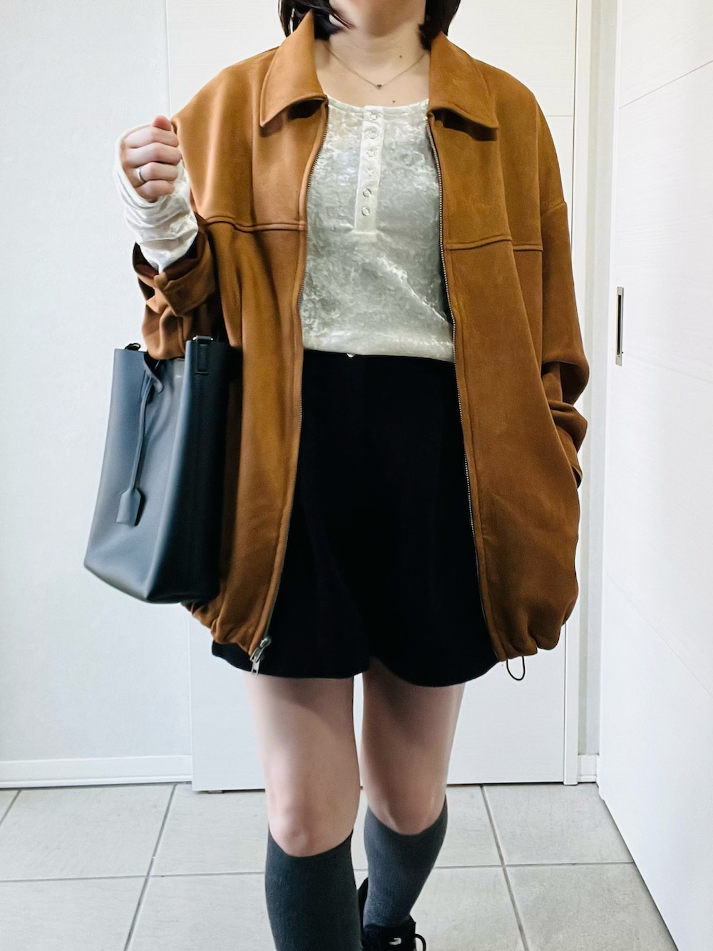 ホワイト系のTシャツ/カットソー、ベージュ系のブルゾン、ブラック系のスニーカーを着用したレディースの春コーディネートの2枚目の写真