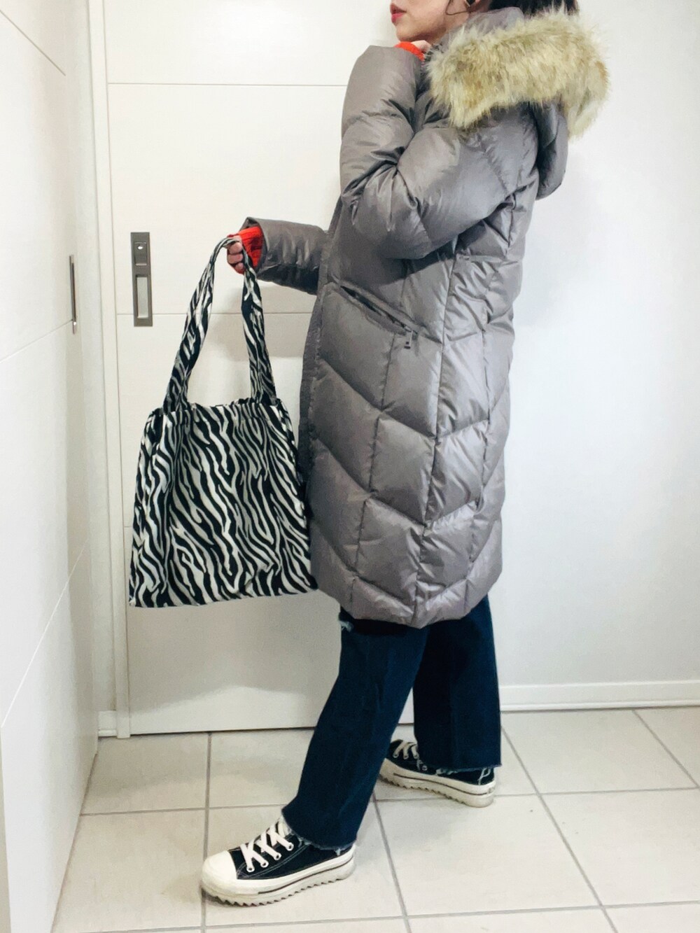 ブラウン系のダウンジャケット/コート、オレンジ系のニット/セーター、ブルー系のデニムパンツを着用したレディースの秋コーディネートの5枚目の写真