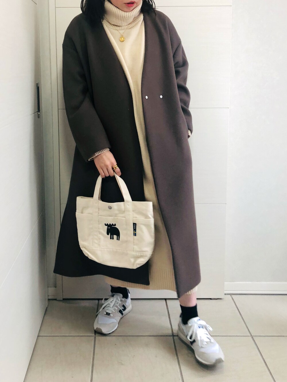 ブラウン系のノーカラーコート、ホワイト系のワンピース、ホワイト系のスニーカーを着用したレディースの秋コーディネートの4枚目の写真