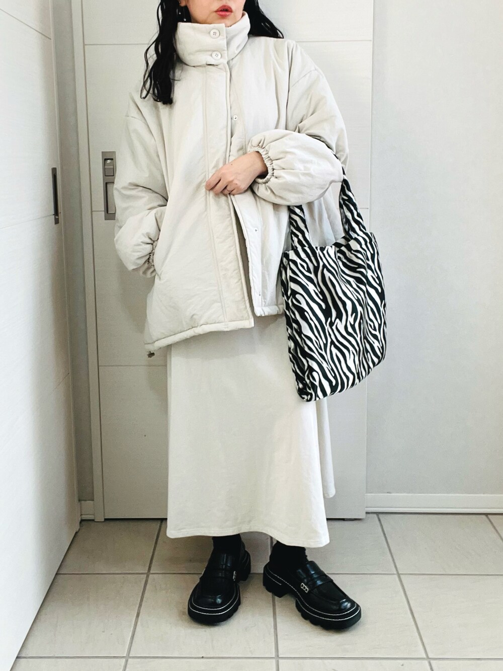 ホワイト系のブルゾン、ホワイト系のワンピース、ブラック系のローファーを着用したレディースの秋コーディネートの4枚目の写真
