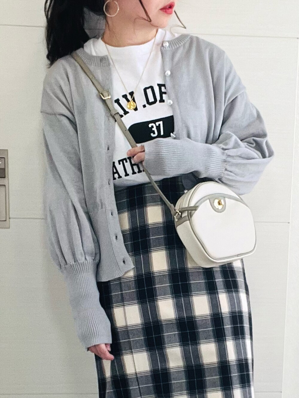グレー系のカーディガン/ボレロ、ホワイト系のTシャツ/カットソー、ブラック系のスカートを着用したレディースの冬コーディネートの2枚目の写真