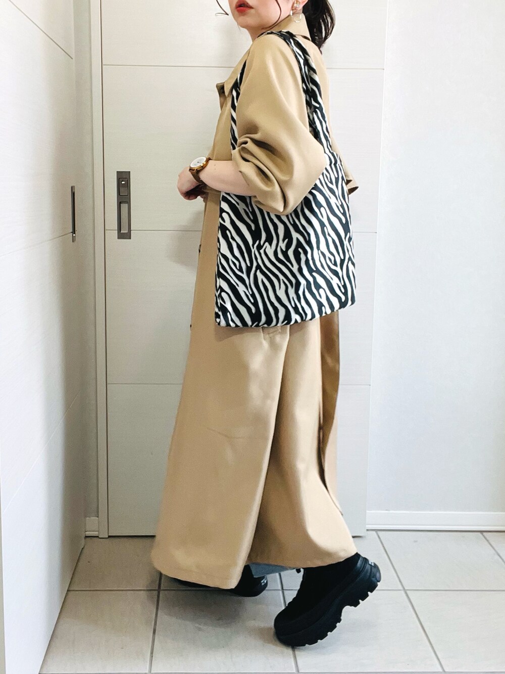 ベージュ系のトレンチコート、ブラック系のキャミソール、ブルー系のデニムパンツを着用したレディースの春コーディネートの4枚目の写真