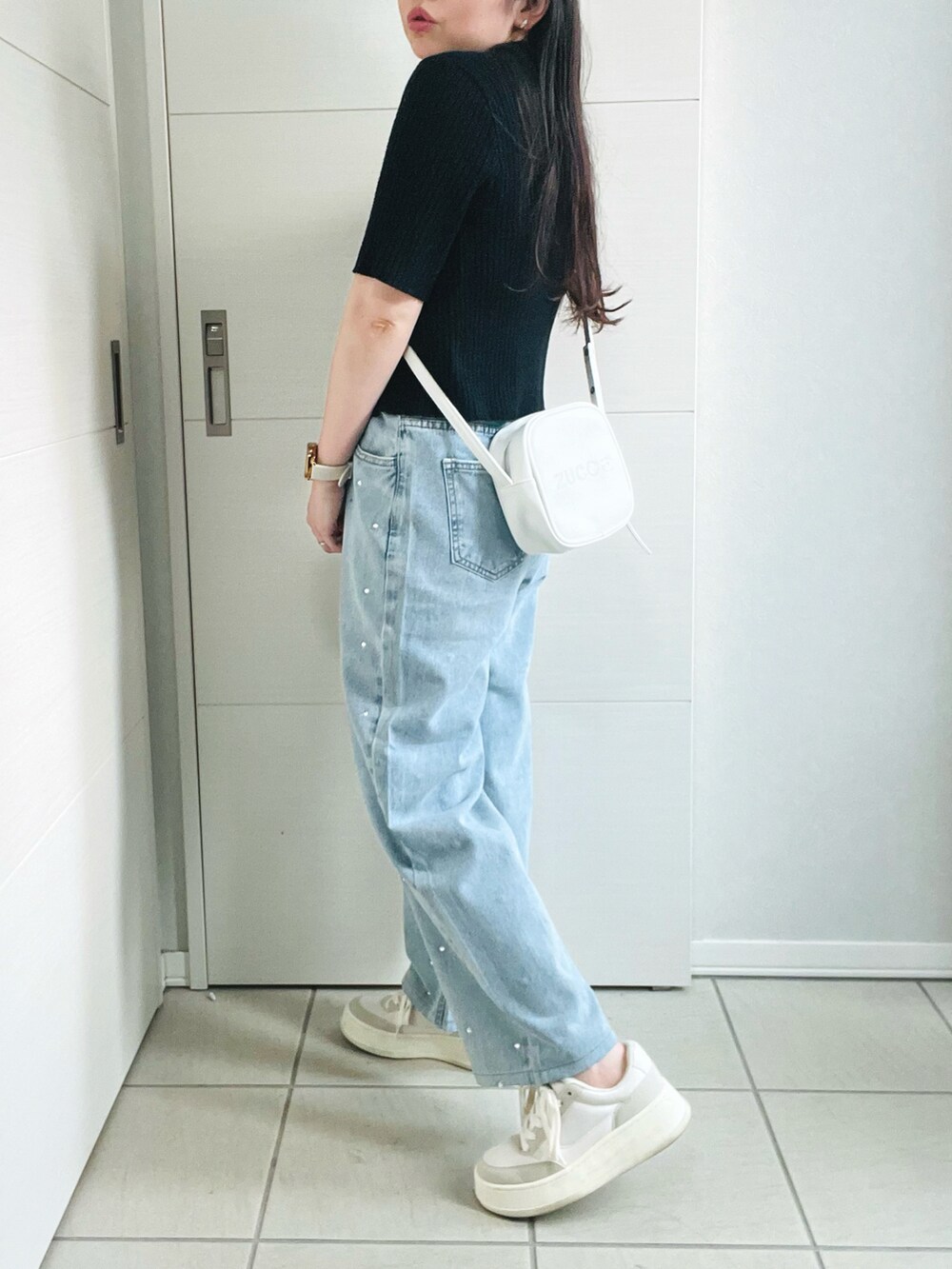 ブラック系のニット/セーター、ホワイト系のキャミソール、ブルー系のデニムパンツを着用したレディースの夏コーディネートの5枚目の写真