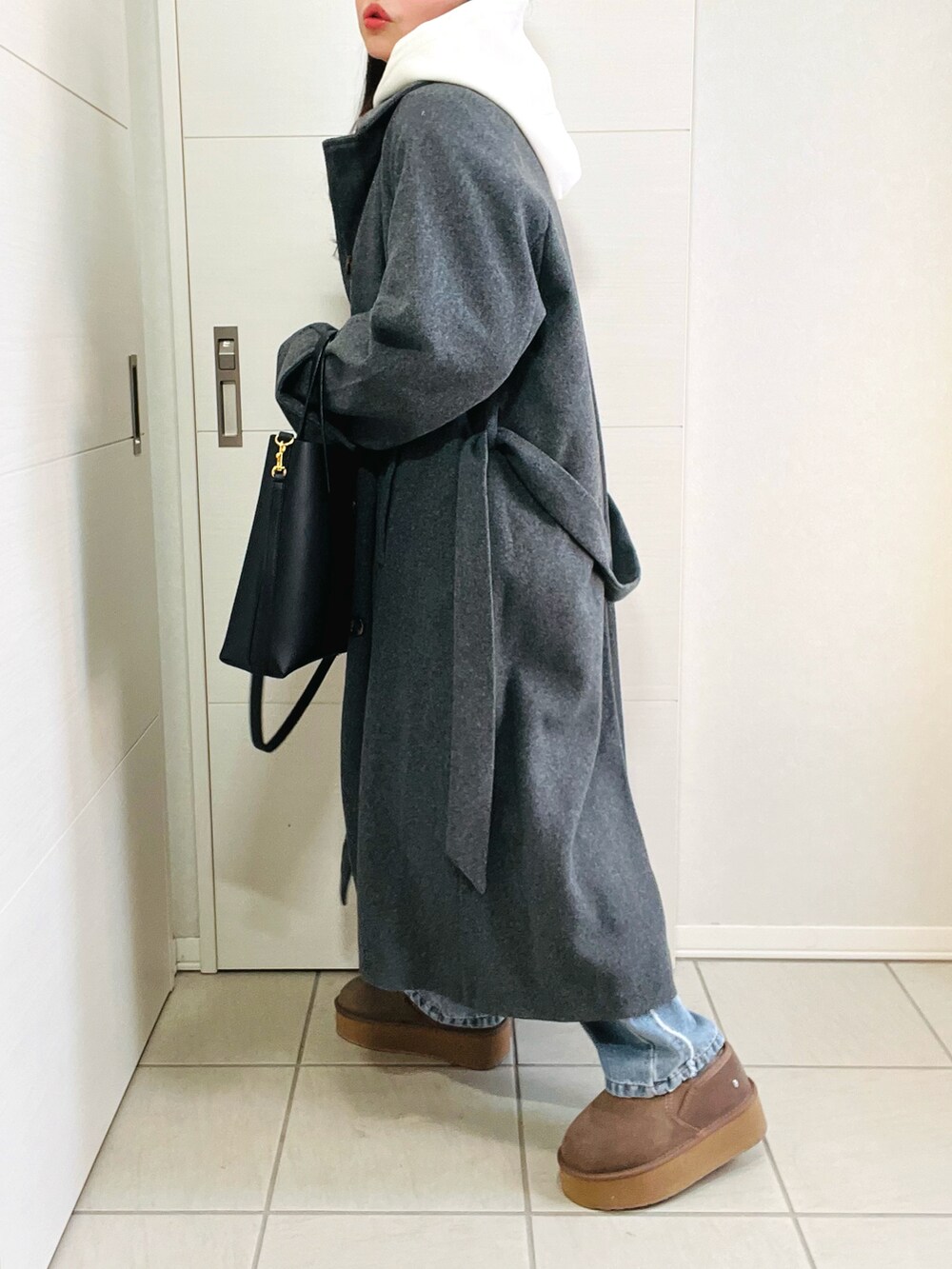 ホワイト系のパーカー、グレー系のステンカラーコート、ブルー系のデニムパンツを着用したレディースの冬コーディネートの3枚目の写真