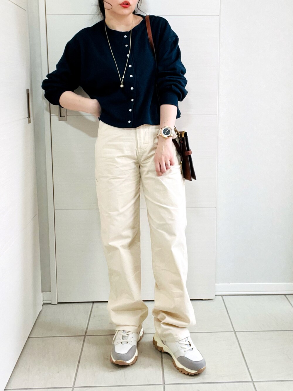 ホワイト系のデニムパンツ、ブルー系のカーディガン/ボレロ、ベージュ系のスニーカーを着用したレディースの春コーディネートの3枚目の写真