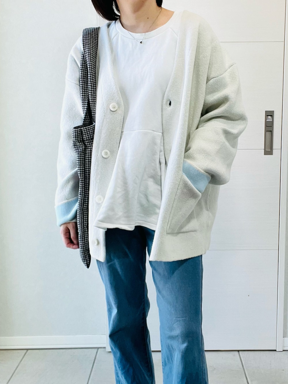 ホワイト系のカーディガン/ボレロ、ブルー系のデニムパンツ、ブラック系のトートバッグを着用したレディースの春コーディネートの2枚目の写真