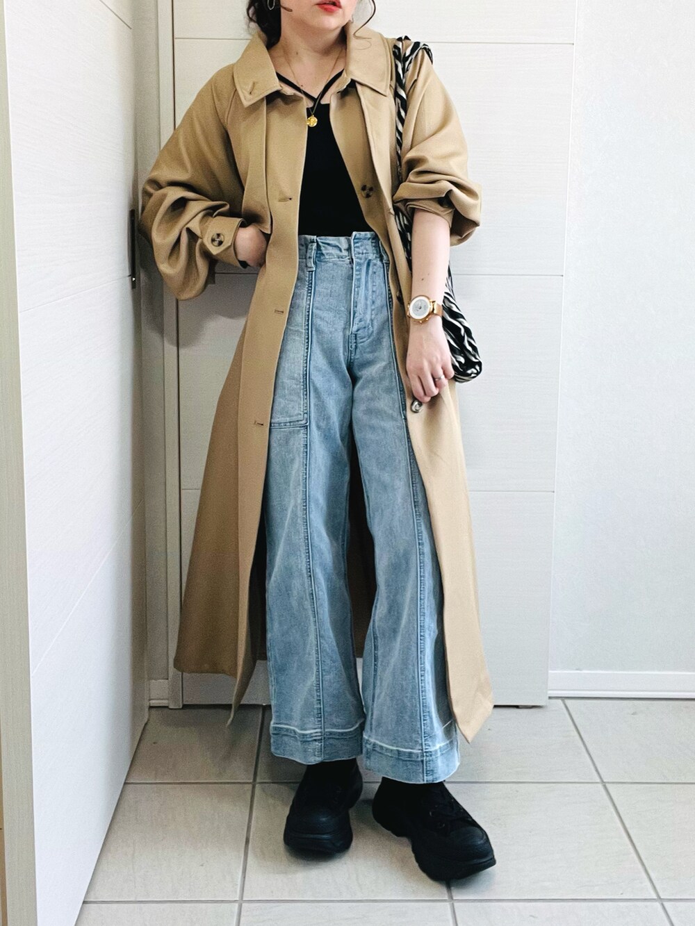 ベージュ系のトレンチコート、ブラック系のキャミソール、ブルー系のデニムパンツを着用したレディースの春コーディネートの3枚目の写真