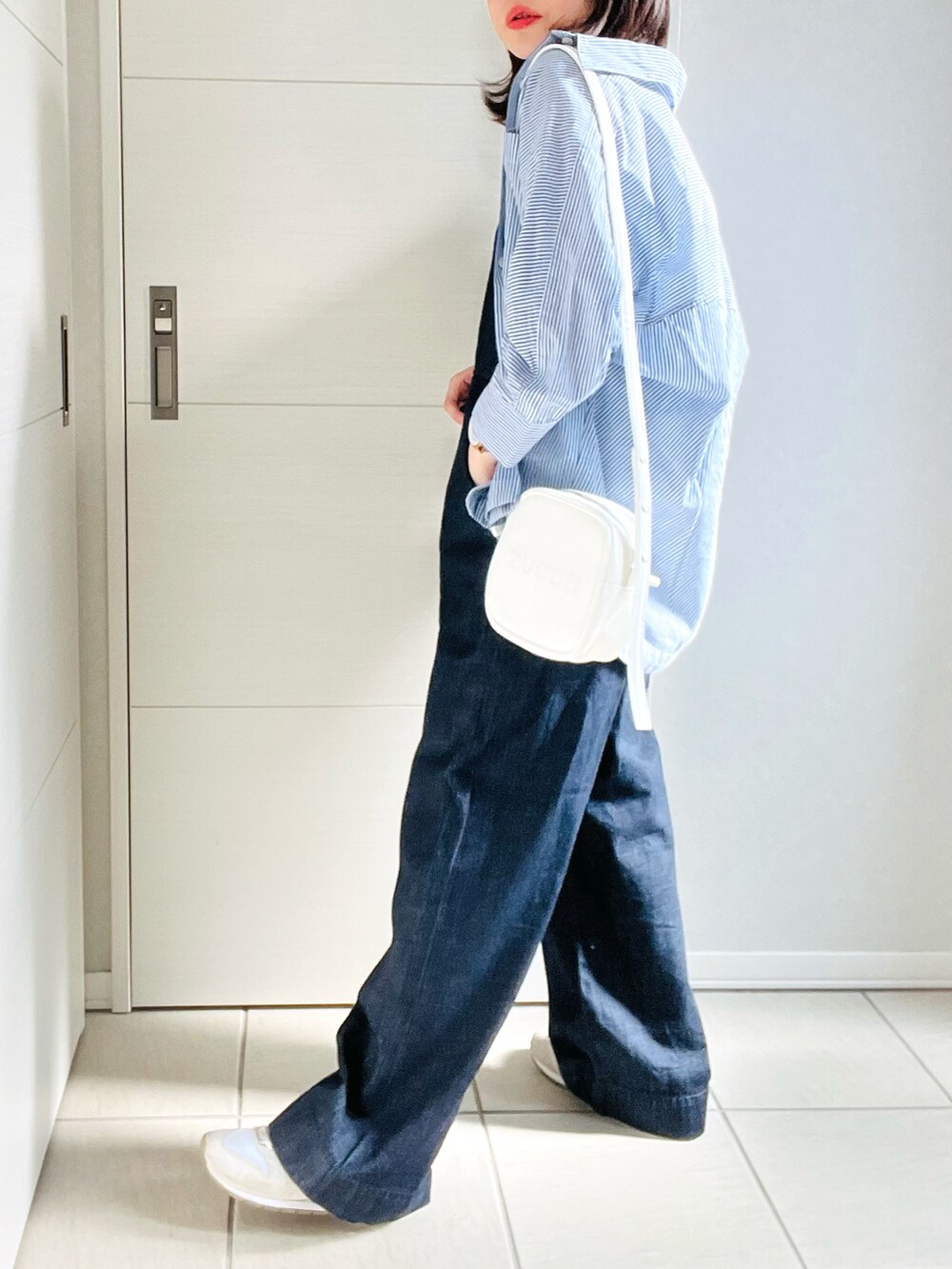 ブルー系のシャツ/ブラウス、ブルー系のサロペット/オーバーオール、ホワイト系のスニーカーを着用したレディースの夏コーディネートの3枚目の写真