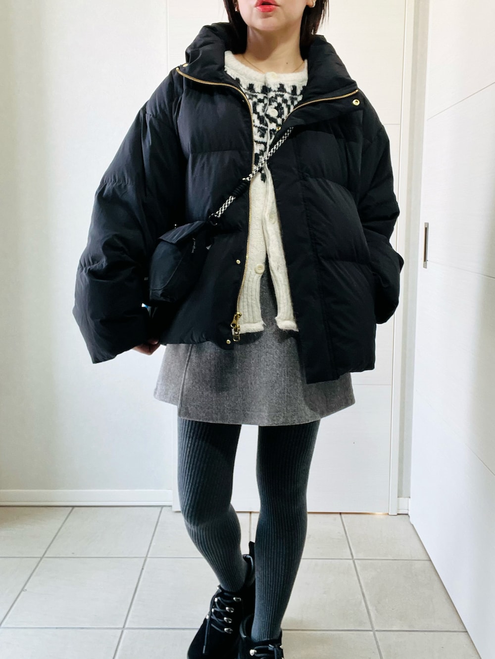 ブラック系のダウンジャケット/コート、ブラック系のブーツ、ホワイト系のカーディガン/ボレロを着用したレディースの春コーディネートの4枚目の写真