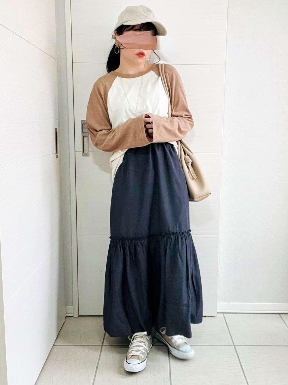 ホワイト系のマウンテンパーカー、ブラウン系のTシャツ/カットソー、グレー系のスカートを着用したレディースの春コーディネートの2枚目の写真