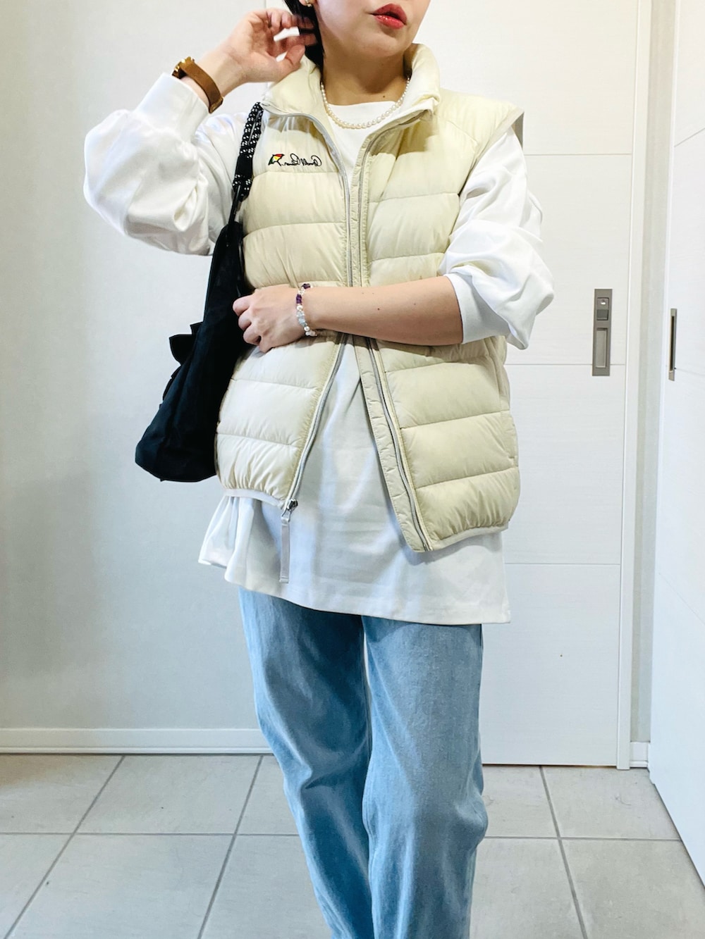 ホワイト系のダウンベスト、ホワイト系のTシャツ/カットソー、ブルー系のデニムパンツを着用したレディースの秋コーディネートの2枚目の写真