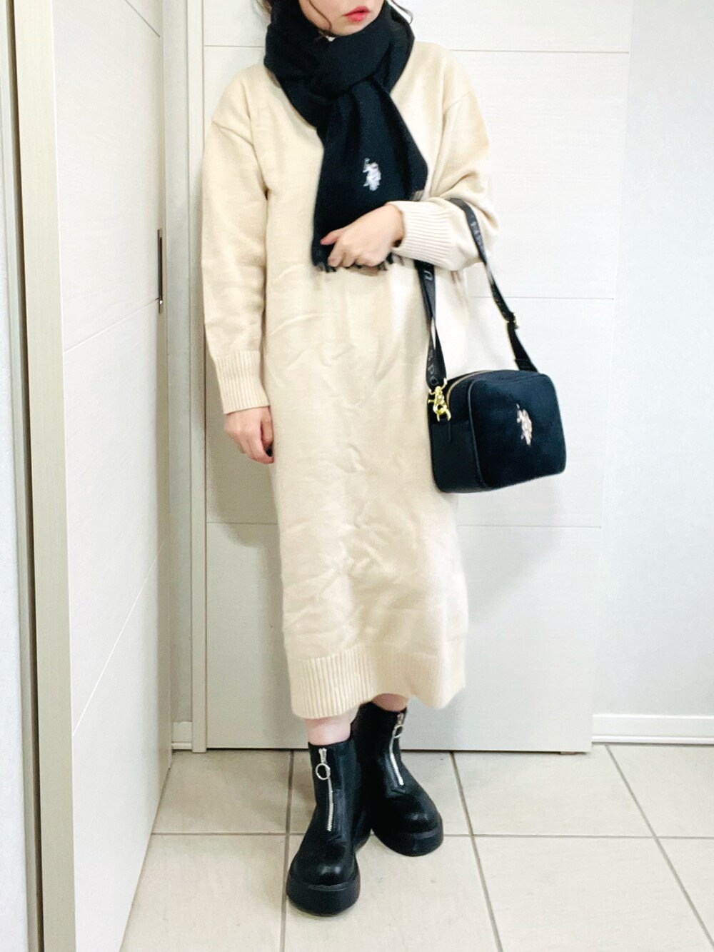 ブラック系のショルダーバッグ、ブラック系のブーツ、ホワイト系のワンピースを着用したレディースの秋コーディネートの3枚目の写真